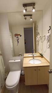 y baño con aseo, lavabo y espejo. en Papudo Laguna, Hermoso Apartamento junto al Mar, en Papudo