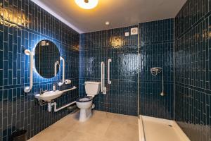 baño con paredes de azulejos azules, aseo y lavabo en The Anchorage, en Poole