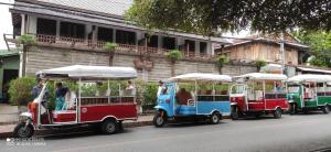 three trolleys driving down a street next to a building at Villa Chitchareune 2 in Luang Prabang