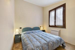 a bedroom with a bed with a blue comforter and a window at Ultimo Tiro-appartamento Terzo Tiro in Cisano sul Neva