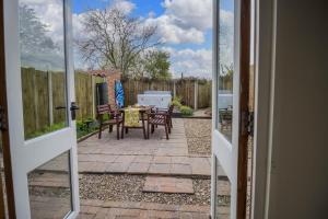 a door leading to a patio with a table and chairs at Beautiful 04 Berth Cottage With A Private Hot Tub In Norfolk Ref 99002hc in Pentney