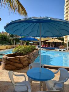 a blue table and chairs with an umbrella next to a swimming pool at Locação Caldas Novas 1105 in Caldas Novas