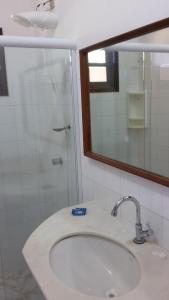 y baño con lavabo y ducha con espejo. en Imbassai Flat en Imbassai