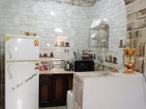 a kitchen with a refrigerator and a white brick wall at Fekry home in Aswan