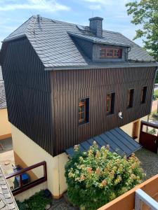 ein Haus mit schwarzem Dach auf einem Garten in der Unterkunft Ferienhaus "Kleines Domizil" Altenberg - direkt im Zentrum von Altenberg gegenüber vom Skilift in Kurort Altenberg