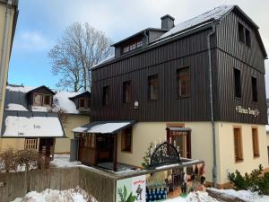 ein Gebäude mit einem schwarzen Dach mit Schnee auf dem Boden in der Unterkunft Ferienhaus "Kleines Domizil" Altenberg - direkt im Zentrum von Altenberg gegenüber vom Skilift in Kurort Altenberg