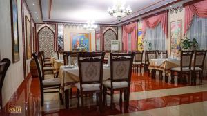 a dining room with tables and chairs and paintings on the walls at Hotel Asia Samarkand in Khodzha-Akhrar