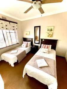 a bedroom with two beds and a ceiling fan at Perna Perna Lodge St Lucia in St Lucia