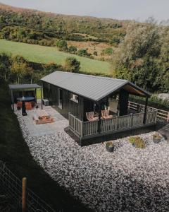a log cabin with a deck and a table and chairs at Briarfield Farm Stays - A Unique Coastal Getaway in Glenarm