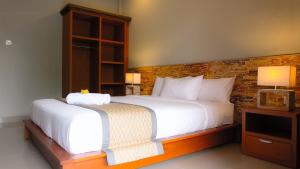a bedroom with a white bed and a brick wall at Kubu De Uma in Seminyak