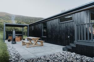 a patio with a picnic table next to a black building at Briarfield Farm Stays - A Unique Coastal Getaway in Glenarm