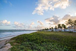 a beach with palm trees and the ocean at Condomínio Villa Belém em Intermares por Carpediem in Cabedelo