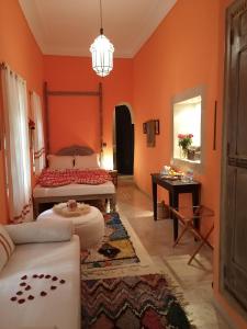 a living room with orange walls and a bed and a table at Dar al Sultan in Marrakesh