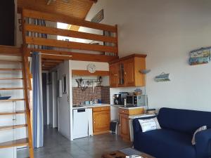 Una sala de estar con un sofá azul y una cocina. en Appartement Pour 4 Personnes Avec Vue Sur L ocean- Residence Le Signal, en Capbreton