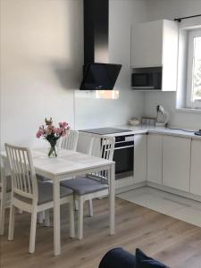 biała kuchnia z białym stołem i krzesłami w obiekcie Apartament IGA w Białej Podlaskiej