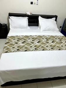 uma cama grande com lençóis brancos e almofadas em Swiss Cottage em Kribi