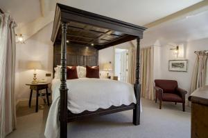 a bedroom with a large bed and a chair at The Swan Hotel in Bibury