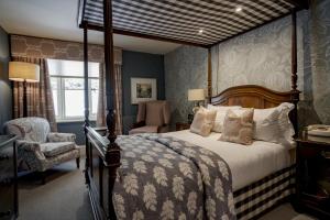 a bedroom with a canopy bed and a chair at The Swan Hotel in Bibury