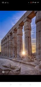 un gran edificio con columnas con una puesta de sol en el fondo en Masa House en Luxor