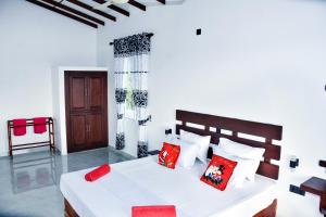 sypialnia z dużym białym łóżkiem z czerwonymi poduszkami w obiekcie Indika's Apartment w mieście Hikkaduwa