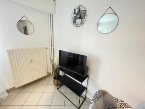 salon z telewizorem i lustrami na ścianie w obiekcie Vue sur Jardin Parking Ascenseur Un-Séjour-à-Part w Metz