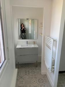 une femme prenant une photo d'une salle de bains dans l'établissement Au 154 Bis - Joli Appartement avec Grande Terrasse et proche de la plage à Malo, à Dunkerque