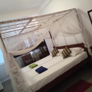 a bedroom with a white bed with a canopy at The Ocean in Galle