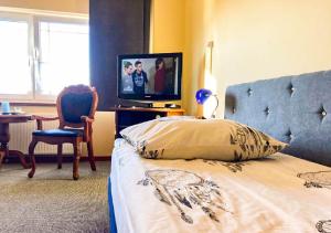 1 dormitorio con 1 cama, TV y silla en Noclegi Prestige, en Siewierz