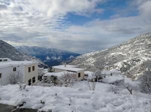 un pueblo cubierto de nieve con montañas en el fondo en El Nogal en Bubión