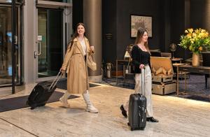 two women walking through a building with their luggage at Intercontinental London - The O2, an IHG Hotel in London