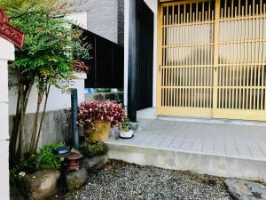 eine Haustür eines Hauses mit Blumen und Pflanzen in der Unterkunft 湯庵 完全貸し切り庭付き in Matsue