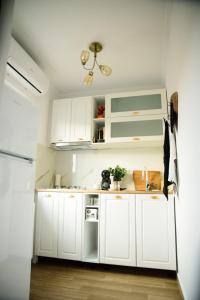 a kitchen with white cabinets and a refrigerator at Studio Sofia in Râmnicu Vâlcea