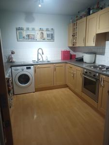a kitchen with a sink and a washing machine at Double Room in a Top Floor Shared Apartment in Northampton