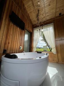 - une grande baignoire blanche dans une chambre avec fenêtre dans l'établissement Pousada- Cabana Gala Vale das Macieiras Urubici, à Urubici