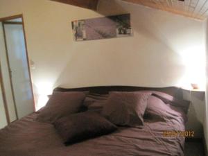 a bed with brown pillows in a bedroom at Les Chênes 2 - cadre verdoyant in Eugénie-les-Bains +5 photos