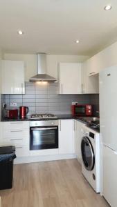 a kitchen with white cabinets and a washer and dryer at Large 6 bedroom duplex - perfect for large family in Liverpool