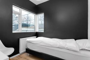 a black bedroom with a bed and a window at Relaxing Reykjavik Apartment in Reykjavík