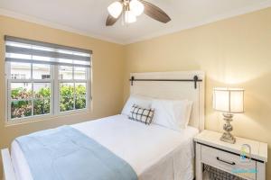 a bedroom with a bed with a ceiling fan and a window at Dover Court Apartments - Steps to St Lawrence Gap in Christ Church