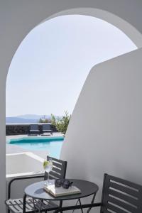 une terrasse avec une table et des chaises ainsi qu'une piscine dans l'établissement Mr and Mrs White Santorini, à Oia