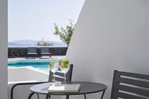 uma mesa com dois copos de vinho e um livro em Mr and Mrs White Santorini em Oia