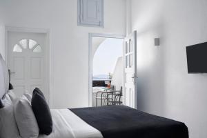 a bedroom with a bed and a door leading to a balcony at Mr and Mrs White Santorini in Oia