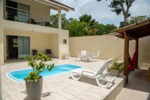 una casa y un patio con piscina y sillas en Quintal da Arte Suites, en Arraial d'Ajuda