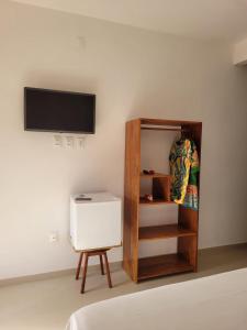 Habitación con cama, estante y TV. en POUSADA TOCA DO LOBO, en Isla de Boipeba