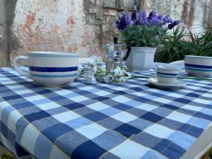 una tovaglia a quadri blu e bianchi con due tazze e dei fiori di Casa Ziu Juanne a Orosei