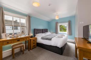 a bedroom with a bed and a desk and a television at Bower House Inn in Eskdale