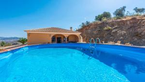 a large blue swimming pool in front of a house at Casa Cuatro Vientos Almogía by Ruralidays in Almogía