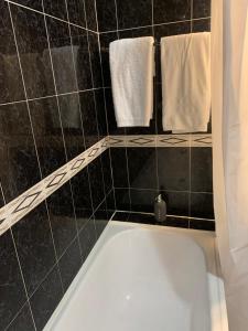 a bathroom with a white tub and black tiles at Casa De Cha Prazeres in Prazeres