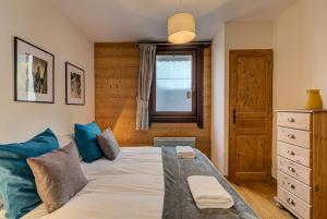 een slaapkamer met een bed met blauwe kussens en een raam bij Apartment le Paradis 1 - Alpes Travel - Central Chamonix (sleeps 4) in Chamonix-Mont-Blanc