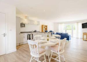 una mesa de comedor blanca con sillas blancas y una cocina en The Cottages at Ivy Farm by Charles Alexander Short Stay en Lytham St Annes