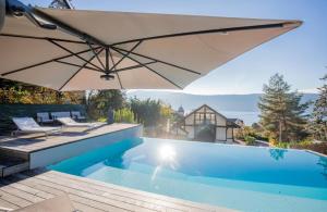 einen Pool mit Sonnenschirm neben einem Haus in der Unterkunft Centre Veyrier du Lac, Luxueux appartement vue lac Annecy et PISCINE, LLA Selections by Location lac Annecy in Veyrier-du-Lac